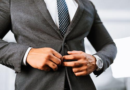 Closeup shot of a businessman buttoning his jacket in an office