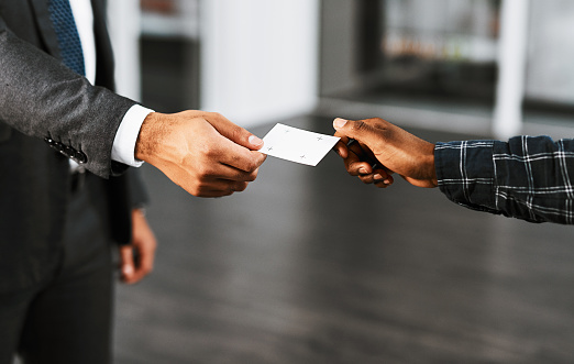 Closeup shot of two businesspeople exchanging business cards in an office