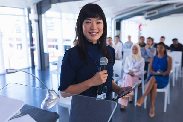 istock Female speaker with digital tablet speaks in business seminar 1163704043