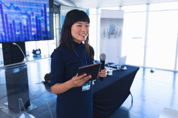 istock Female speaker with digital tablet speaks in business seminar 1163704055