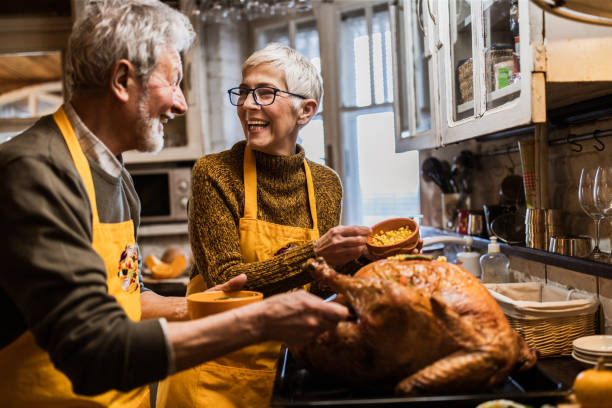 istock Happy senior couple talking while decorating turkey on Thanksgiving day. 1163704565