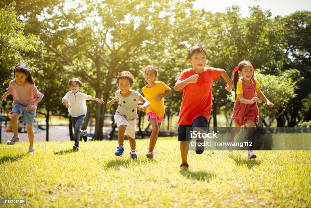 Grupo multi-ethnic de crianças da escola que riem e que funcionam - Foto de stock de Criança royalty-free