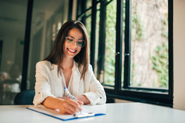 Smiling elegant businesswoman or student filling application form. Smiling elegant businesswoman or student filling application form. filling out stock pictures, royalty-free photos & images