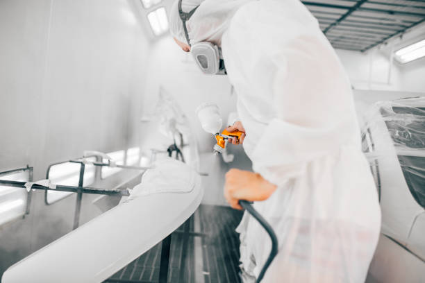 istock Car painter in protective work wear painting part. 1163707090