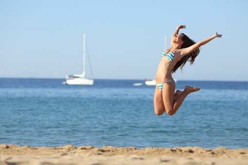 Excited girl in bikini jumping on the beach