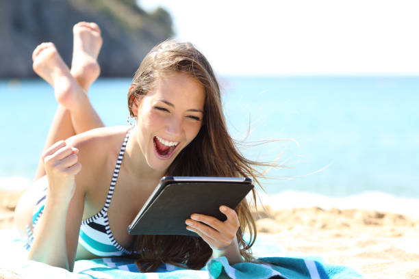 возбужденная девушка в бикини проверяет планшет на пляже - child beach digital tablet outdoors стоковые фото и изображения