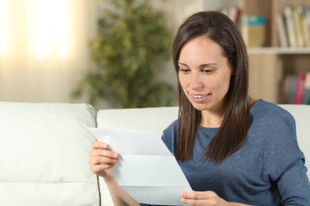 istock Woman reading a letter on a couch at home 1163707522