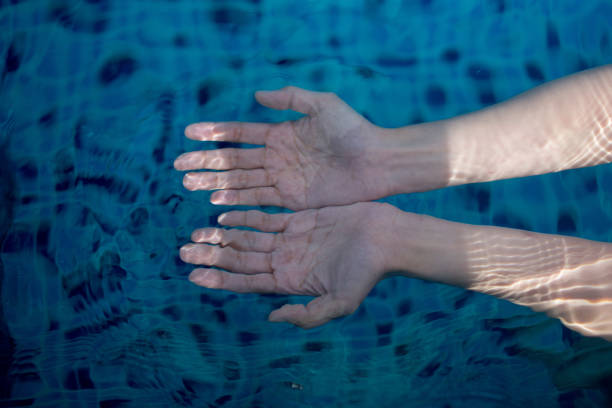 istock woman's hand in pool, turquoise water 1163709015