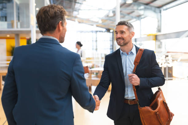 Businessmen shaking hands with each other in office Front view of happy Caucasian businessmen shaking hands with each other in office. International diverse corporate business partnership concept sales executive stock pictures, royalty-free photos & images