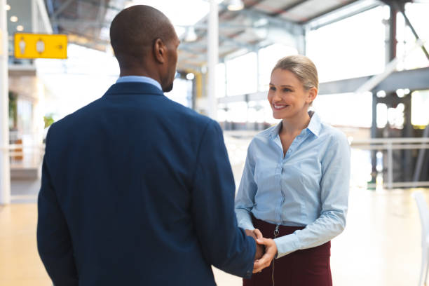 istock Business people interacting with each other in corridor at office 1163711189