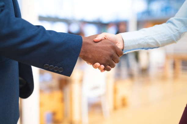 uomini d'affari che si stringono la mano l'uno con l'altro nel corridoio dell'ufficio - handshake foto e immagini stock