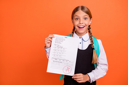 Portrait of her she nice attractive lovely charming cute cheerful cheery, successful glad pre-teen blonde girl demonstrating great grade isolated on bright vivid shine orange background