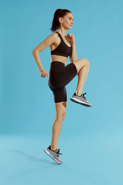 istock Fitness workout. Woman exercising, jumping on blue background 1163717063