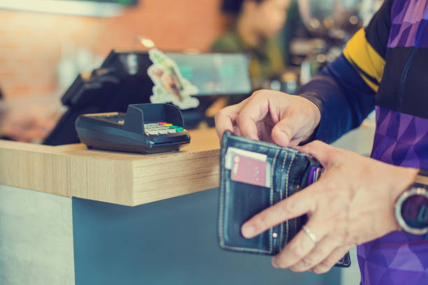 istock Selective focus to credit card reader with blurry the man picking up banknotes or credit card in the wallet to pay at the counter service. 1163718572