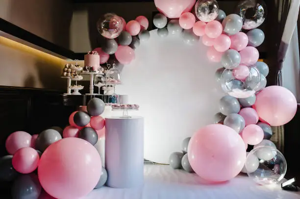 Photo of Delicious wedding reception. Birthday Cake on a background balloons party decor. Copy space. Celebration concept. Trendy Cake. Candy bar. Table with sweets, candies, dessert.