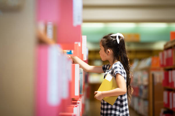 menina que escolhe um livro em uma estante - reading girl - fotografias e filmes do acervo