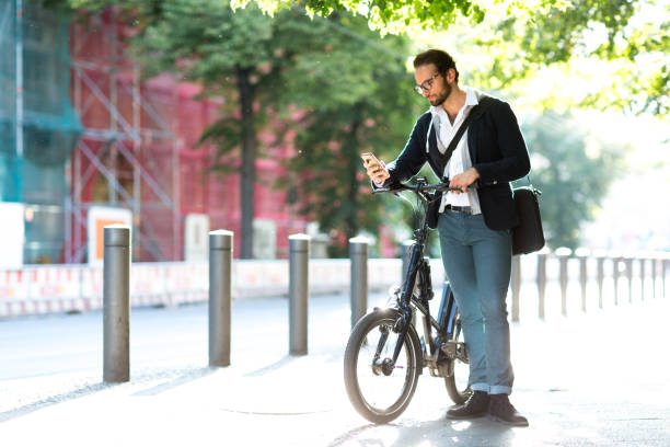 istock Businessman using smart phone while standing next to his electric bicycle 1163720726
