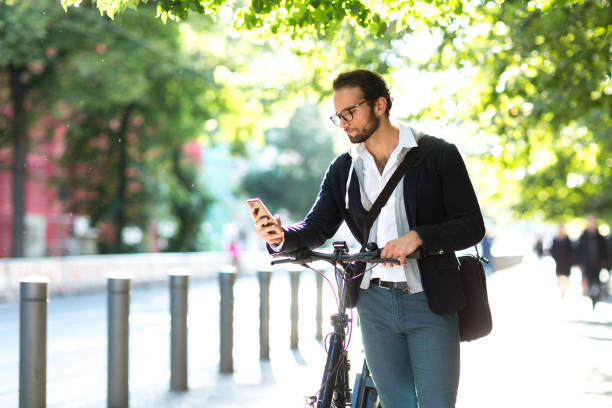 istock Businessman using smart phone while standing next to his electric bicycle 1163720839