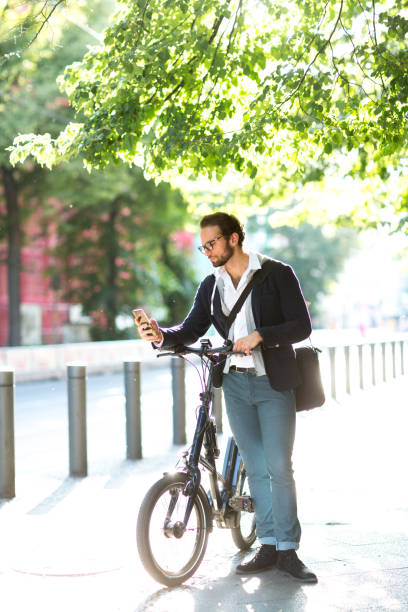 istock Businessman using smart phone while standing next to his electric bicycle 1163720844