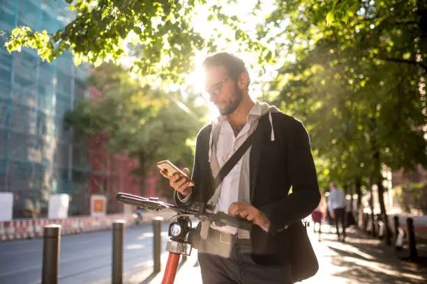 Photo series of a young adult male commuting with electric bicycle through Berlin and doing business at the same time, drinking coffee from reusable coffee cup, listening to podcasts and making business calls.