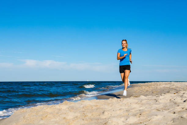 istock Young woman running on beach 1163722458