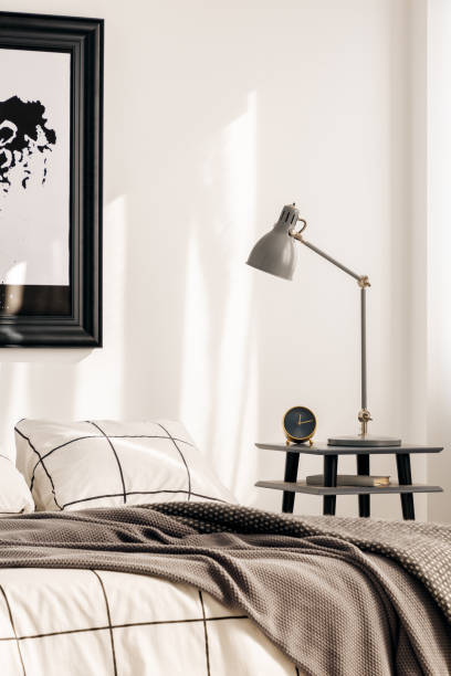istock Industrial lamp on nightstand table next to king size bed in white bedroom interior 1163723172