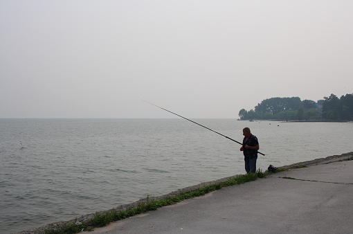 Russia, Novosibirsk, July 21, 2019: fisherman fishing with fishing rods on the waterfront near the hydroelectric dam in the summer day
