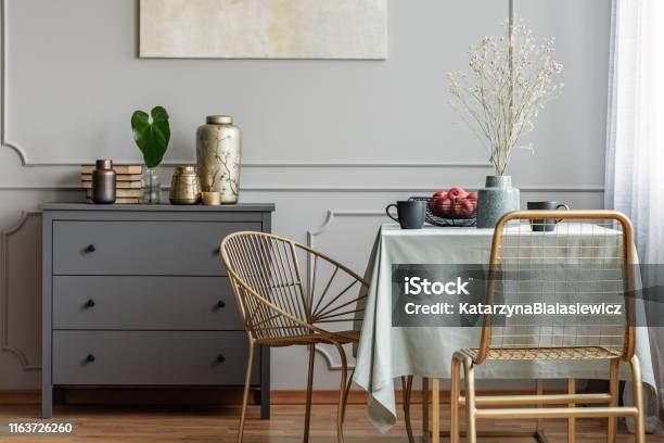 Dining Room Interior With Long Table Stylish Golden Chairs And Grey Wooden Commode Stock Photo - Download Image Now