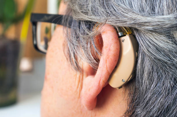istock Elderly grey-haired woman with a hearing aid and glasses. Selective focus, close-up. 1163728078