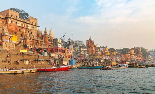 Varanasi ancient city architecture with river ghat at sunset with as seen from a boat on the river Ganges