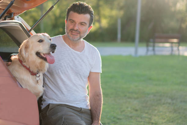 istock Man sitting with his dog on the car trunk 1163730860