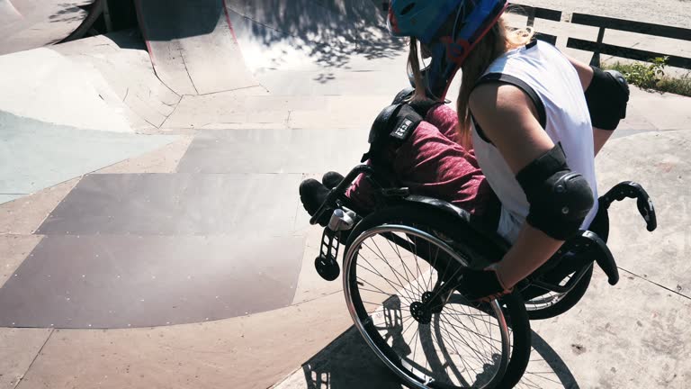 Generation-Z woman in wheelchair in skate park doing stunts - slow motion video