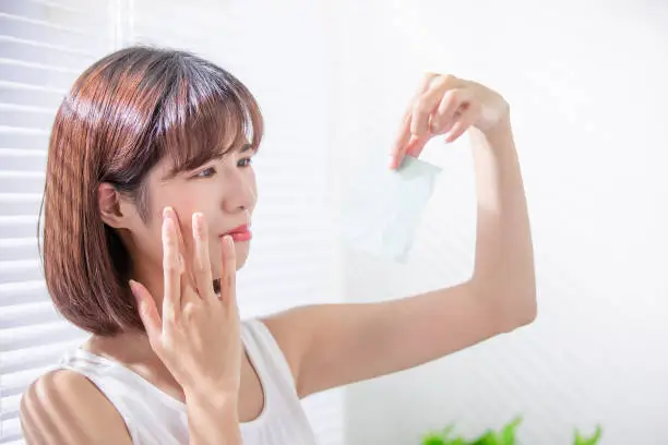 Photo of woman use oil blotting paper