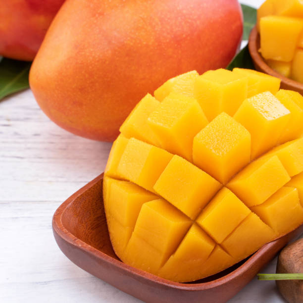 istock Fresh chopped mango on a tray and bright rustic wooden background. Tropical summer fruit design concept. 1163736555