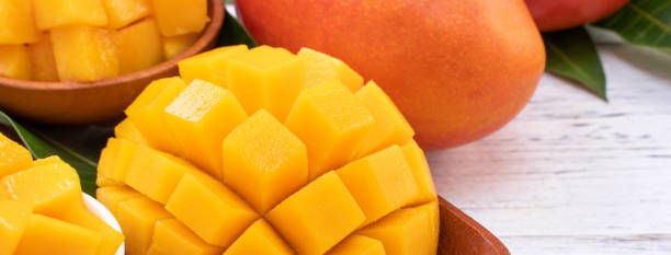 istock Fresh chopped mango on a tray and bright rustic wooden background. Tropical summer fruit design concept. 1163736560