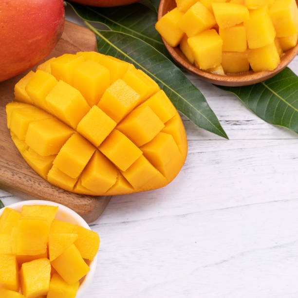 istock Fresh chopped mango on a tray and bright rustic wooden background. Tropical summer fruit design concept. 1163736568