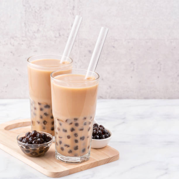 istock Tapioca pearl ball bubble milk tea in drinking glass with straw on marble white table and wooden tray. 1163736576