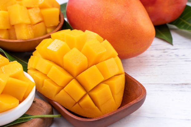 istock Fresh chopped mango on a tray and bright rustic wooden background. Tropical summer fruit design concept. 1163736577