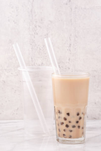 istock Tapioca pearl ball bubble milk tea in drinking glass with straw on marble white table and wooden tray. 1163736594