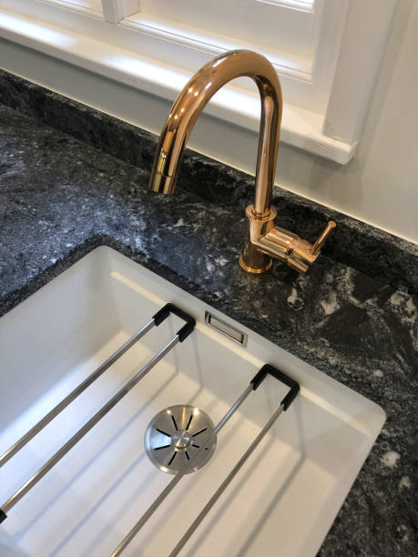 istock Image of modern kitchen with rectangular single bowl kitchen butler sink with victorian style bronze mixer tap , white ceramic sink with black granite worktop countertop 1163739341