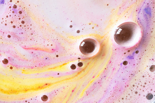 Foam with round bubble of bath bomb close-up colorful background