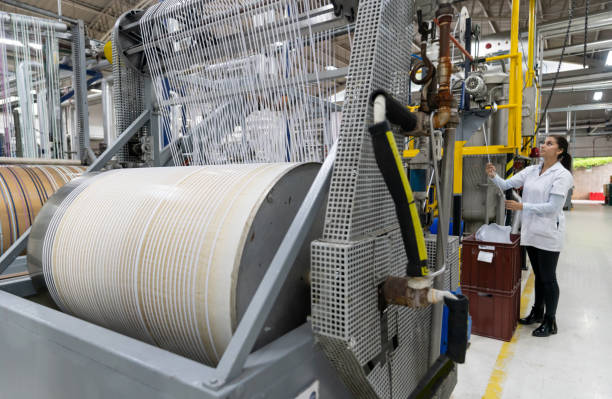 Machine operating at a textile factory and woman doing quality control - industrial concepts