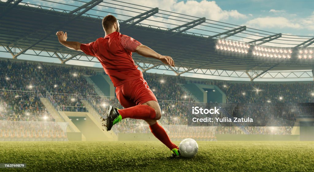 Soccer player kicks a ball Professional soccer player with a ball in action. Soccer stadium with tribunes and fans cheering. Sports event Soccer Stock Photo