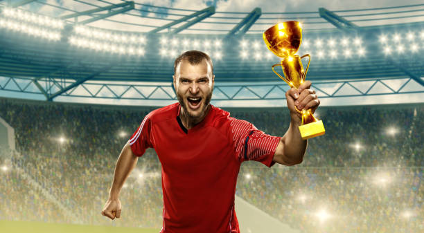 istock Soccer player celebrates victory and holds a champions cup 1163749880