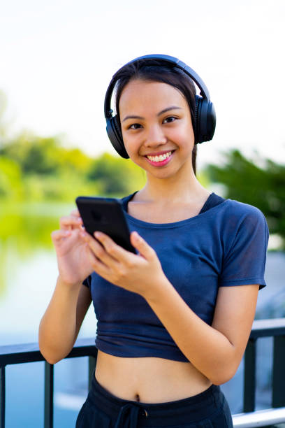 joven corredor asiático usando teléfono inteligente y escuchando música. - filipino ethnicity audio fotografías e imágenes de stock