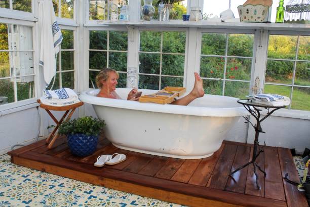 glückliche und entspannte reife frau genießen ihre schöne outdoor-badewanne - soaking tub stock-fotos und bilder