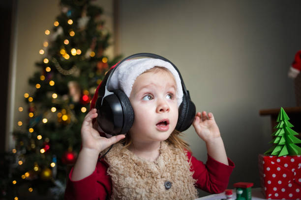 enfant dans des écouteurs écoutant la musique sur l'arrière-plan de l'arbre de noel. audio bébé. chanson de la nouvelle année - christmas tree audio photos et images de collection