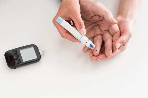 Cropped view of woman hands measuring blood sugar of senior man