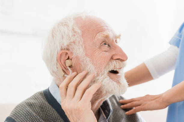 Profile of happy and cheerful man with hearing aid in ear, looking away Profile of happy and cheerful man with hearing aid in ear, looking away hearing aid photos stock pictures, royalty-free photos & images