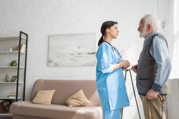 istock Grey haired man talking to nurse, standing in room with copy space 1163755996